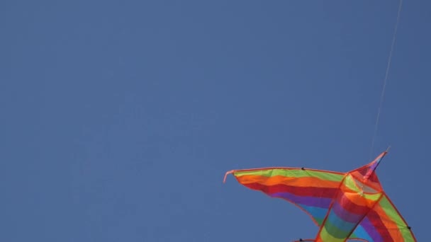 Rückansicht eines hoch in den blauen Himmel fliegenden Drachens aus nächster Nähe. Vogelperspektive — Stockvideo