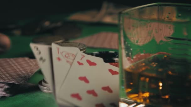 Азартная удача. Покерные фишки казино, монеты и колода игральных карт, сложенных в несколько стопок на столе, карты бросаются на них — стоковое видео