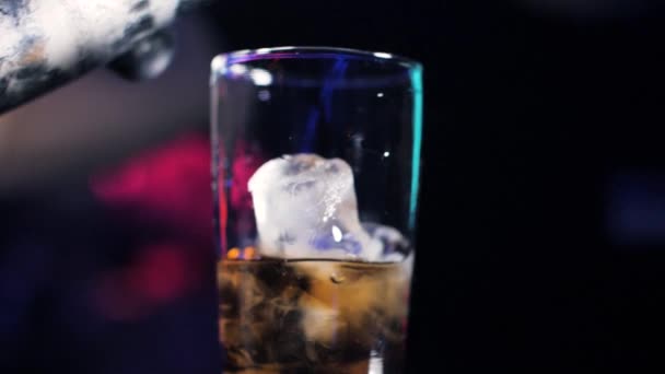 Barman dělá koktejl, nalévá pití do průhledného skla s kostkami ledu. Zpomal. Aerovaná voda Ve skle na černém pozadí. koktejlový večírek, noční život a noční klub. — Stock video