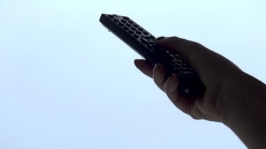 Kadın el beyaz arka plan üzerinde izole bir tv uzaktan kumanda işletim