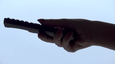 Kadın el beyaz arka plan üzerinde izole bir tv uzaktan kumanda işletim