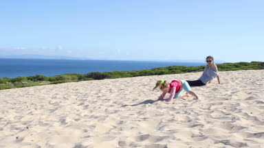 komik sahne: dört yaşında sarışın mutlu kız ters takla atarak çalışıyor ya da amuda kumul annesi, Valdevaqueros Beach, Tarifa, Cadiz, Endülüs, İspanya, Europe yanında tarih