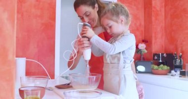 Helezon ve yardım, yumurta ile elektrikli karıştırıcı bir kristal kase içine kırbaçlanan kadın anne ile dört yaşında kız 