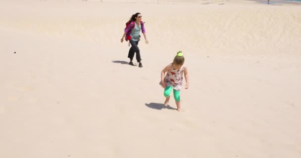 四岁的金发女孩与礼服与黑发妇女母亲与背包漫步在沙滩沙子在加斯 安大路西亚 西班牙 — 图库视频影像