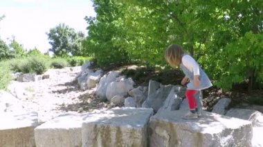 Büyük taş bloklar Madrid İspanya genel Manzanares park, taş bir nehir üzerinde yürüyen oynayan üç yaşında sarışın çocuk kot elbise ve pembe tayt ile