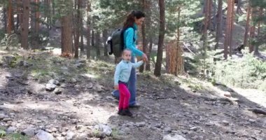 4k video. Yaş dört yıl bir iz Guadarrama Dağları, Madrid, İspanya'nın kırsal kesimde ormandaki atlamak için annesine elini tutarak, yürüyüş, oynayan sarışın kız