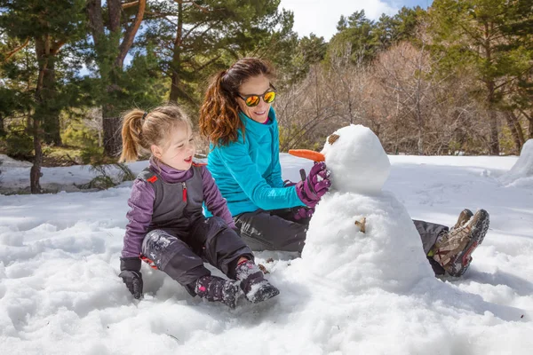 Glückliche Familie Vierjähriges Blondes Mädchen Und Frau Sitzen Auf Schnee Stockfoto