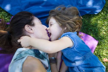 Dört yaşında sarışın çocuk havlu park yeşil çim yatan kadın anne ısırmaya çalışıyor