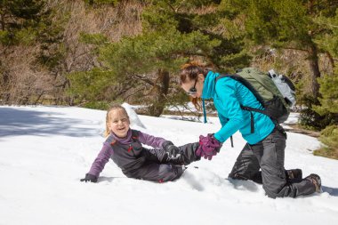önyükleme için komik onun kızı, dört yaşında sarışın kız, doğada kar üzerinde oturan yerleştirerek kadın