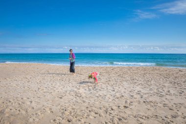 kadın ve dört yıl yaşlı çekme ve deniz kabukları, kum plaj sahil Bolonia Beach, Cadiz, Endülüs, İspanya, Avrupa'nın toplama kız.