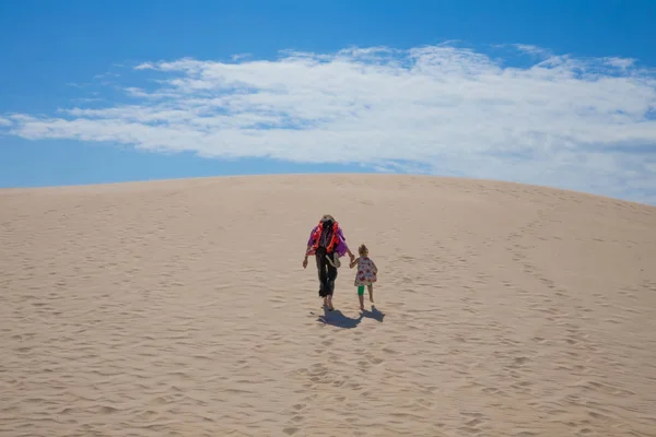 女人背着她的女儿 四岁的金发碧眼的女孩 走在沙滩上 在塔里法 加的斯 安达卢西亚 西班牙的海滩波洛尼亚的沙丘 复制或文本空间 — 图库照片