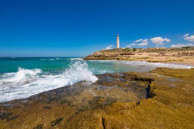 güzel manzara: deniz feneri Canos fırlayan (Barbarte, Cadiz, Endülüs, İspanya yakınındaki Trafalgar Cape in yanındaki sahil taş kırma dalga okyanus)