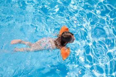 dört yaşında sarışın çocuk mavi güzel havuzu suda yüzen omuz omuza, kollukları, turuncu flatör kollu havai çekim