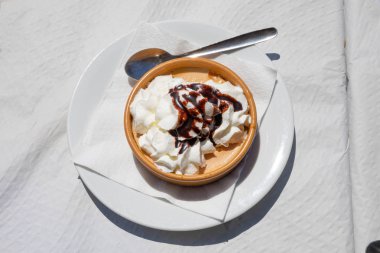 kabak mus ve krem üzerinde dairesel seramik küçük crockpot kaşıkla restoranda beyaz masa örtüsü üzerinde yemeye hazır çikolata sosu ile