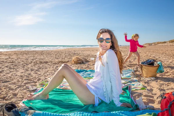 Gelukkige Vrouw Met Zonnebril Kijken Zittend Handdoek Naast Haar Dochter — Stockfoto