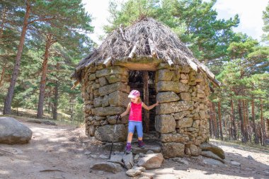 küçük çocuk, beş yaşında bir kız, kapı çerçeve Canencia orman (Madrid, İspanya, Avrupa antik taş Hut ayakta trekking sopayla dağcı)