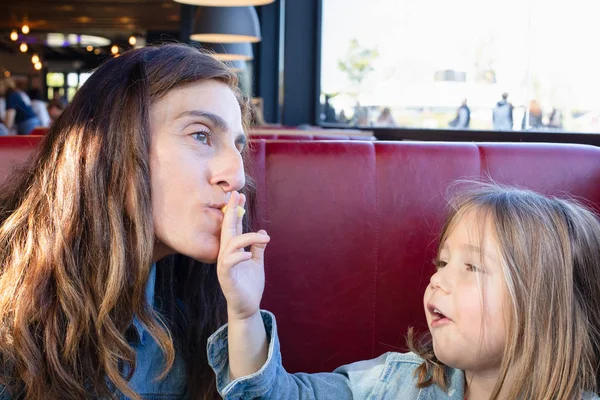 komik atış: beş yaşında sevimli çocuk el ile kanepe kırmızı ve siyah tablo bir restoranda oturan annesi patates kızartması (kızarmış patates dilimlenmiş) verilmesi