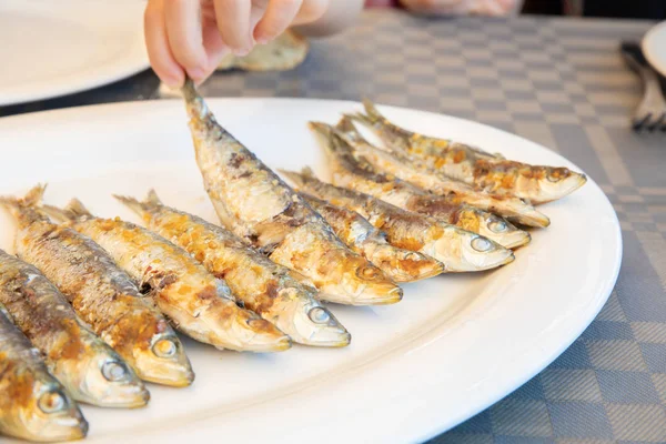 Mano Niña Atrapando Una Sardina Cocinada Cola Gran Plato Blanco —  Fotos de Stock