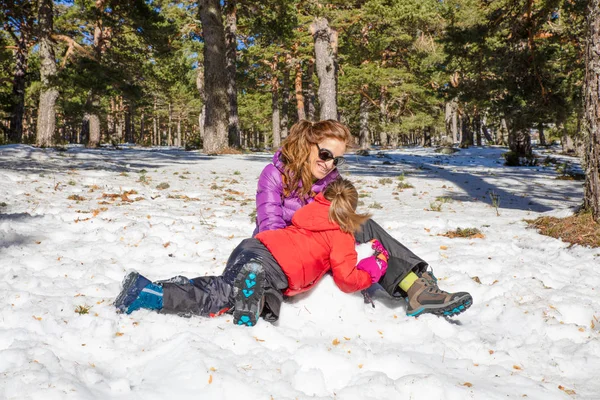Жінка і її маленька дочка сміються на снігу — стокове фото