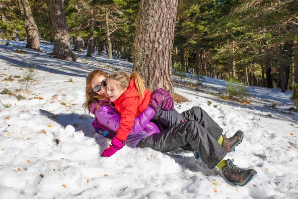 Женщина и девушка обнимаются, лежа на снегу — стоковое фото