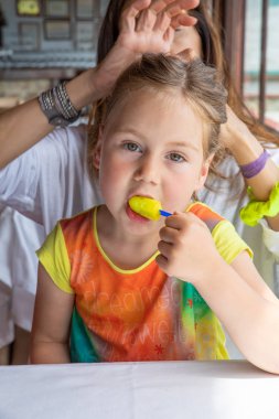 sevimli küçük kız buz lolly yeme ve anne oturuyor arıyorum 