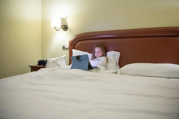 king bed with little girl watching tablet at night