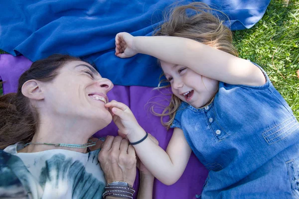 Ένα μικρό κορίτσι και μια μητέρα να παίζουν και να γελάνε ξαπλωμένοι στο πάρκο — Φωτογραφία Αρχείου