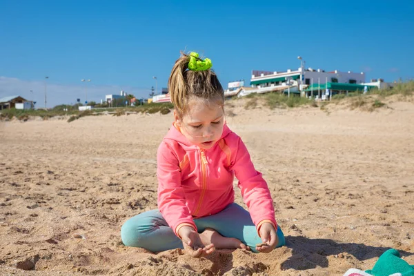 Kleines Mädchen spielt mit Sand am Strand von El Palmar — Stockfoto