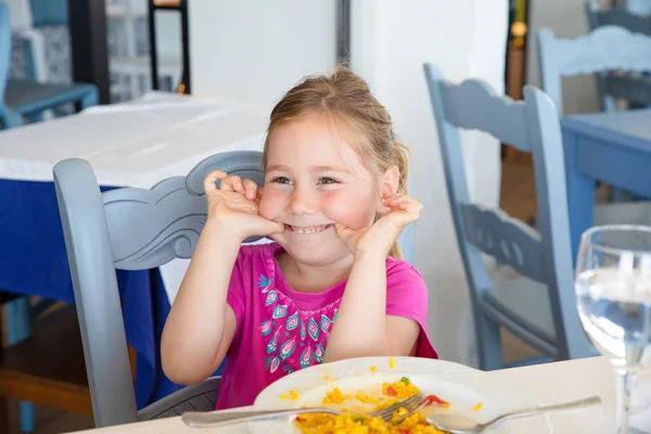 little girl making fun with paella dish in restaurant