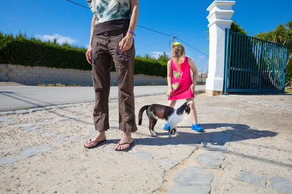 White and black cat between little girl and woman — Stock Photo, Image