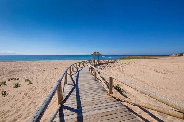 Lång kurva trä strandpromenad gångstig av stranden i Canos Meca — Stockfoto