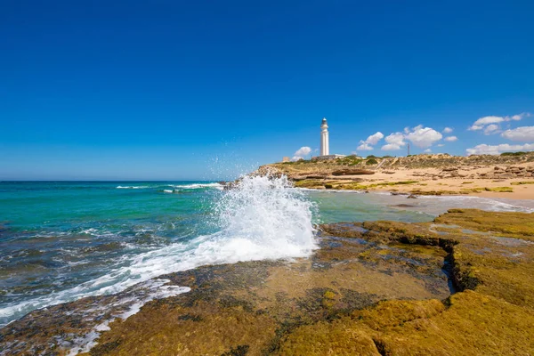 Trafalgar deniz feneri yanında sahil kaya üzerinde dalga kırma — Stok fotoğraf