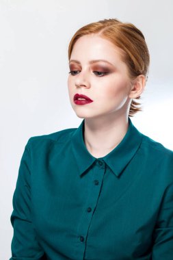 Beyaz bir arka plan üzerinde parlak makyaj ile güzel bir kızıl saçlı kız portresi kapatın. Kadın tepeden bakıyor.