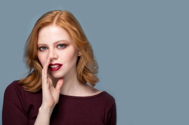 Parlak makyaj ve kıvırcık saçlı bir sır söylemek güzel kızla. Genç portre. Komik kız modeli hakkında bir şeyler fısıldayan.