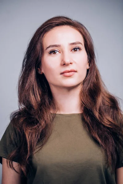 Kameraya gri arka plan üzerinde arayan güzel şirin esmer kadın portresi kapatın.