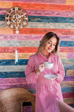 Sabah kahve ve çay. Oturma ve beyaz bir bardak tutan güzel çekici bir kadın. Sevinç, mutluluk, yaşam biçimi