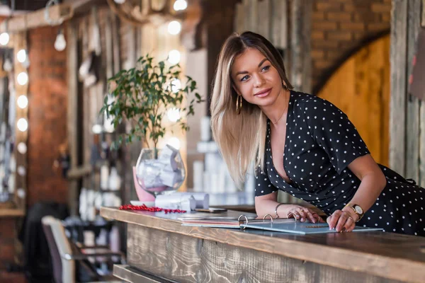 Admin gülümseyen kadın servis menüsünden elini tutar ve bir gülümseme ile müşteriler resepsiyonda karşılıyor.