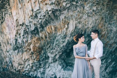 Bir gülümseme ile birbirine, bakarak kayalar, yakınındaki güzel çift sarılmak