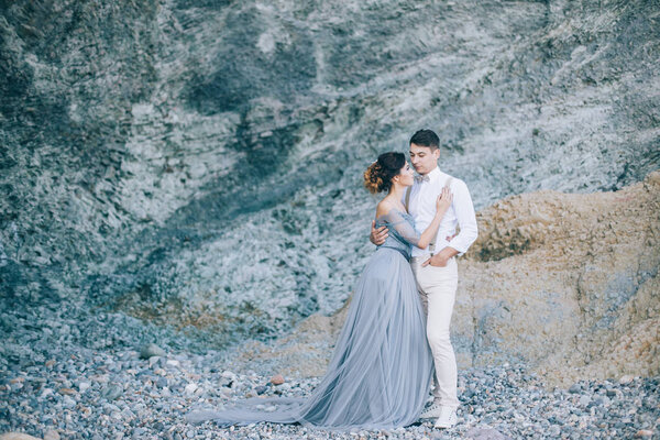Beautiful young couple on their wedding day by the sea near the rock. Happiness, lifestyle, family concept