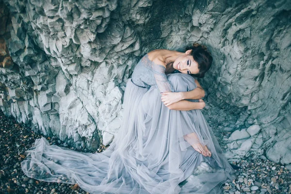 Dizlerinin sarılma uçurum oturan uzun mavi bir elbise içinde güzel kız gelin başını eğdi