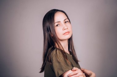 Üzgün ve ciddi kadın kameraya gri arka plan üzerinde arıyor.