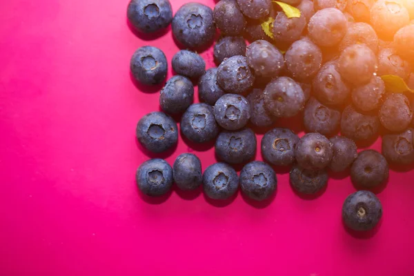 Berries in summer, a source of vitamins. Close up of ripe blueberries on pink background