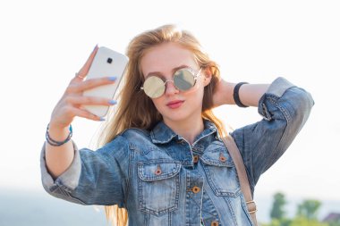 Güzel bir genç sarışın kadının Smartphone'da açık bir selfie alarak yakın çekim