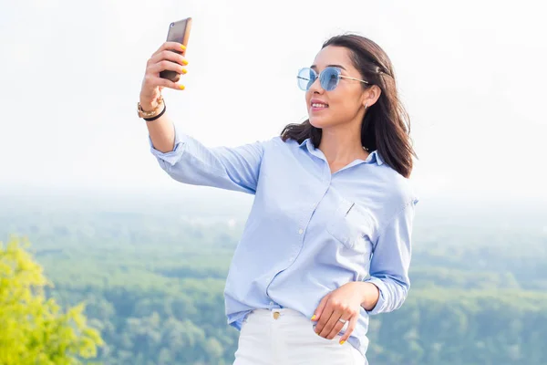 青のメガネで笑顔の美しい女性は 山中の自然の中 Selfies を取る 現代の技術 ライフ スタイル コンセプト — ストック写真