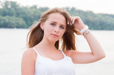 Doğa ve nehrin arka plan üzerinde kameraya bakarak uzun saçlı güzel kadın. Doğal güzellik, gençlik, yaşam tarzı kavramları