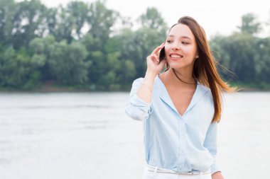 Genç kadın cep telefonu ve gülümsüyor açık havada söz