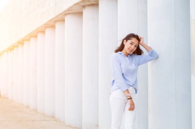 Başarılı esmer kadın gülümseyerek kameraya gri sütun bir arka plan üzerinde batımını alanı Kopyala.