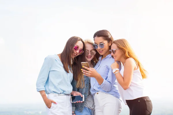 Cuatro Mujeres Jóvenes Con Gafas Sol Usan Teléfonos Inteligentes Techo —  Fotos de Stock