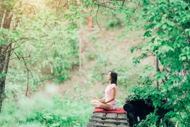Pembe tişört güzel kızı ormanda yoga yapıyor. Sakin ol, dinlenmek, doğa ile uyum