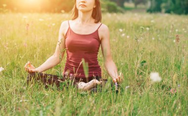 Meditasyon ve yoga sahada. Bordo top güneşin çimenlerin üzerinde oturan bir güzel kadın